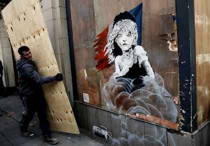 El mural del artista británico Banksy en un campamento de refugiados de Calais, en el momento que es tapado por las autoridades francesas