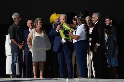 El nuevo presidente de Brasil, Luiz Inácio Lula da Silva, recibe la banda presidencial de manos del líder indígena brasileño y ambientalista Raoni Metuktire, conocido como el Jefe Raoni (atrás), y otros representantes de la comunidad, en el Palacio de Planalto después de su ceremonia de toma de posesión en el Congreso Nacional, en Brasilia, el 1 de enero de 2023