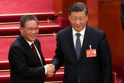El nuevo primer ministro electo de China, Li Qiang, a la izquierda, estrecha la mano al presidente chino Xi Jinping, durante una sesión de la Asamblea Popular Nacional en el Gran Palacio del Pueblo en Beijing, el sábado 11 de amrzo de 2023. (AP Foto/Mark Schiefelbein)