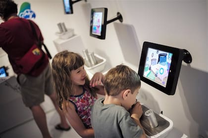 Chicos que siguen una historia en un dispositivo con fragancias, en un museo de Nueva York