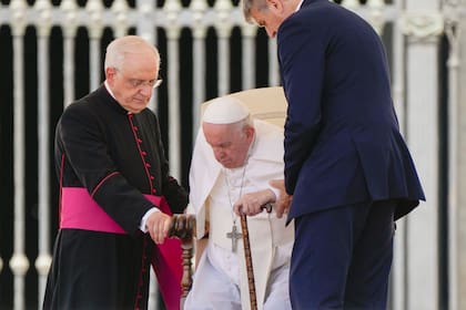 El papa Francisco se para con ayuda de su colaborador, monseñor Leonardo Sapienza