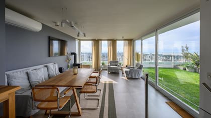 El parque de césped natural, un respiro en medio de la ciudad. Equipararon los tonos de la pared (Sinteplast) y la funda del sillón, y sumaron sillas 'Cesca' con asiento y respaldo de esterilla (Siuk Objetos).