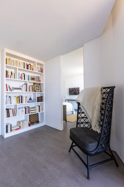 El pasillo que conduce a una de las habitaciones, donde se destacan un sillón de respaldo alto y una biblioteca empotrada. “Necesitamos más espacio porque los dos somos grandes lectores”, revela Patricia.