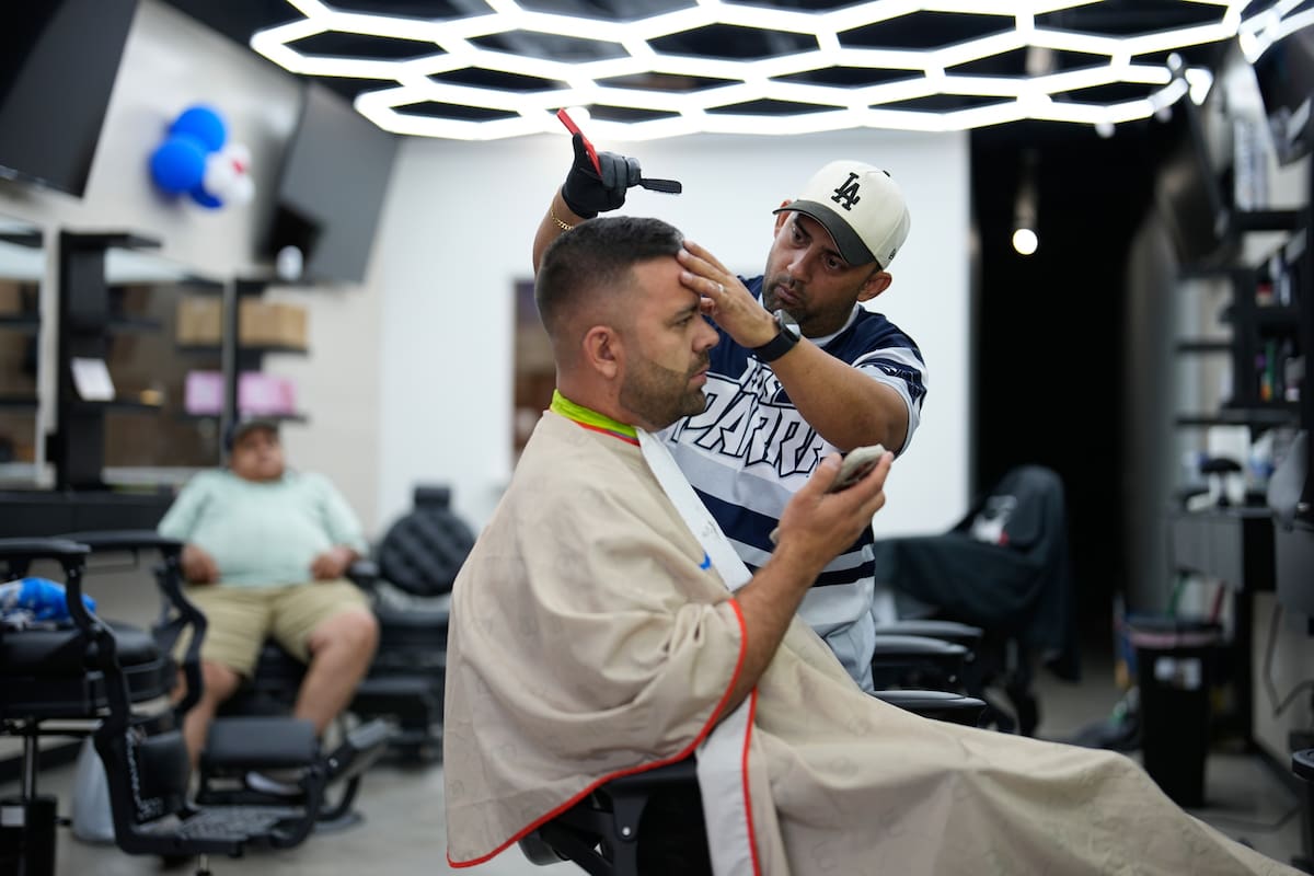 El peluquero Diego Contreras corta el cabello a su compatriota venezolano Diego Parra el miércoles 1