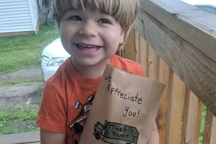 El pequeño John con un refrigerio para su buen amigo el recolector de residuos (Kayla Coleman)