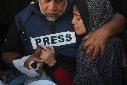 El periodista de Al Jazeera, Wael Dahdouh, sostiene la mano de su hijo, Hamza, que también trabajaba para Al Jazeera y fue asesinado en un ataque israelí, en Rafah, Franja de Gaza, el 7 de enero de 2024