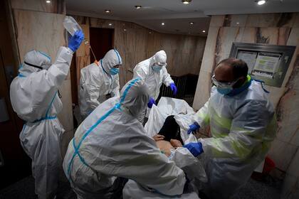 El personal de SUMMA 112 (Servicios de Emergencias Médicas de Madrid) traslada a un hombre con síntomas de coronavirus desde su casa a un hospital en Madrid el 13 de noviembre de 2020