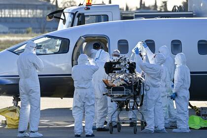El personal médico carga a un paciente infectado con Covid-19 en un avión para una evacuación, en el aeropuerto de Nimes-Garon en Saint-Gilles, el 27 de octubre de 2020