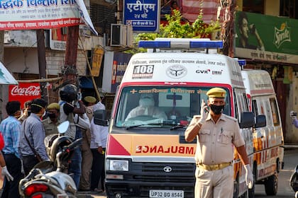 El personal policial escolta una ambulancia que transporta un caso sospechoso de coronavirus, en el área de Teliarganj de Allahabad el 24 de abril de 2020