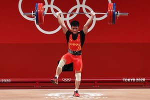 El pesista chino Li Fabin sostiene 166 kilos con una sola pierna.