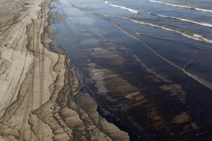 El petróleo contamina la playa Cavero en Ventanilla, Callao, Perú, el martes 18 de enero de 2022, luego de que las altas olas atribuidas a la erupción de un volcán submarino en Tonga provocaran un derrame de petróleo. El Instituto de Defensa Civil del Perú dijo en un comunicado que un barco estaba cargando petróleo en la refinería La Pampilla en la costa del Pacífico el domingo cuando las fuertes olas movieron la embarcación y provocaron el derrame. (Foto AP/Martin Mejía)