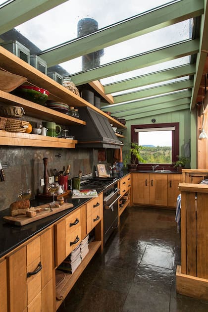 El piso de la cocina es de piedra verde oxidada de 50x5cm, al igual que la pared del fondo y su alzada, y combina bien con las mesadas de granito negro absoluto.