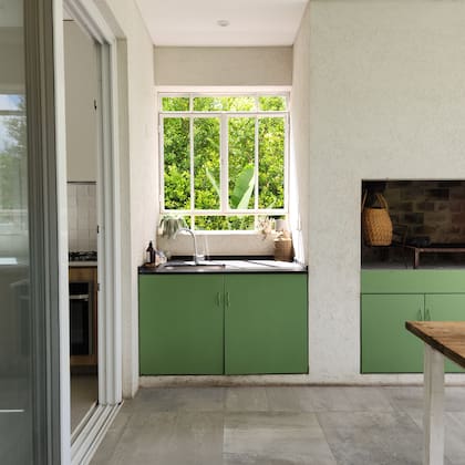 El piso exterior es porcelanato 'Antico Lightgrey' de 60x120 (Vite). Las puertas del sector de parrilla, en principio blancas, fueron pintadas de verde por la dueña de casa.
