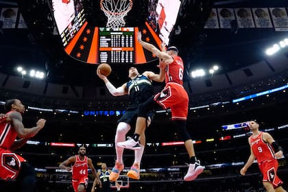 El pívot de los Bucks de Milwaukee Brook López penetra hacia la canasta mientras lo defiende el base de los Bulls de Chicago Alex Caruso, el martes 5 de abril de 2022. (AP Foto/David Banks)