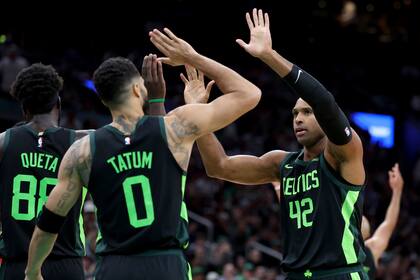 El pívot dominicano de los Celtics de Boston, Al Horford (42) es felicitado por el alero Jayson Tatum (0) luego que Horford recibiera una falta de un jugador de los Raptors de Toronto durante la segunda mitad del juego de baloncesto de la NBA, el sábado 16 de noviembre de 2024, en Boston. (AP Foto/Mark Stockwell)