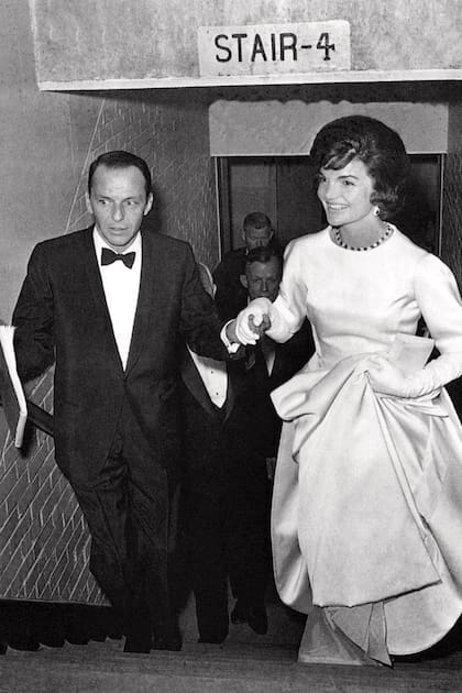 El popular astro acompaña escaleras arriba a la futura primera dama Jacqueline Kennedy durante una gala –organizada por él– y celebrada en la Armería de la Guardia Nacional, en Washington, para ayudar a pagar las deudas de la campaña de John Fitzgerald Kennedy. Era enero de 1961. Más de diez años después, en octubre de 1974, Frankie y Jackie habrían pasado juntos una sola noche: la cita tuvo lugar en una suite del hotel Waldorf Astoria.