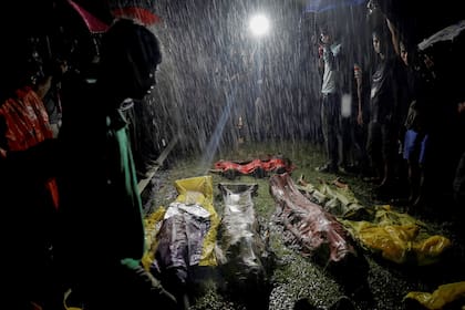Varios refugiados se reúnen bajo fuertes lluvias alrededor de los cuerpos de los refugiados rohingya (28 de septiembre de 2017)