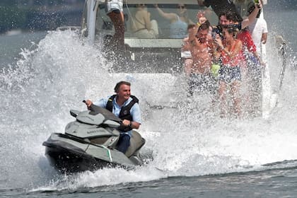 El presidente brasileño Jair Bolsonaro salpica a la gente que participa en un paseo en barco de sus partidarios en el lago Paranoa en Brasilia, el 15 de mayo de 2022.