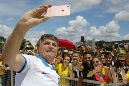 El presidente brasileño Jair Bolsonaro se toma una selfie junto a manifestantes en Brasilia, frente al palacio de la Alvorada