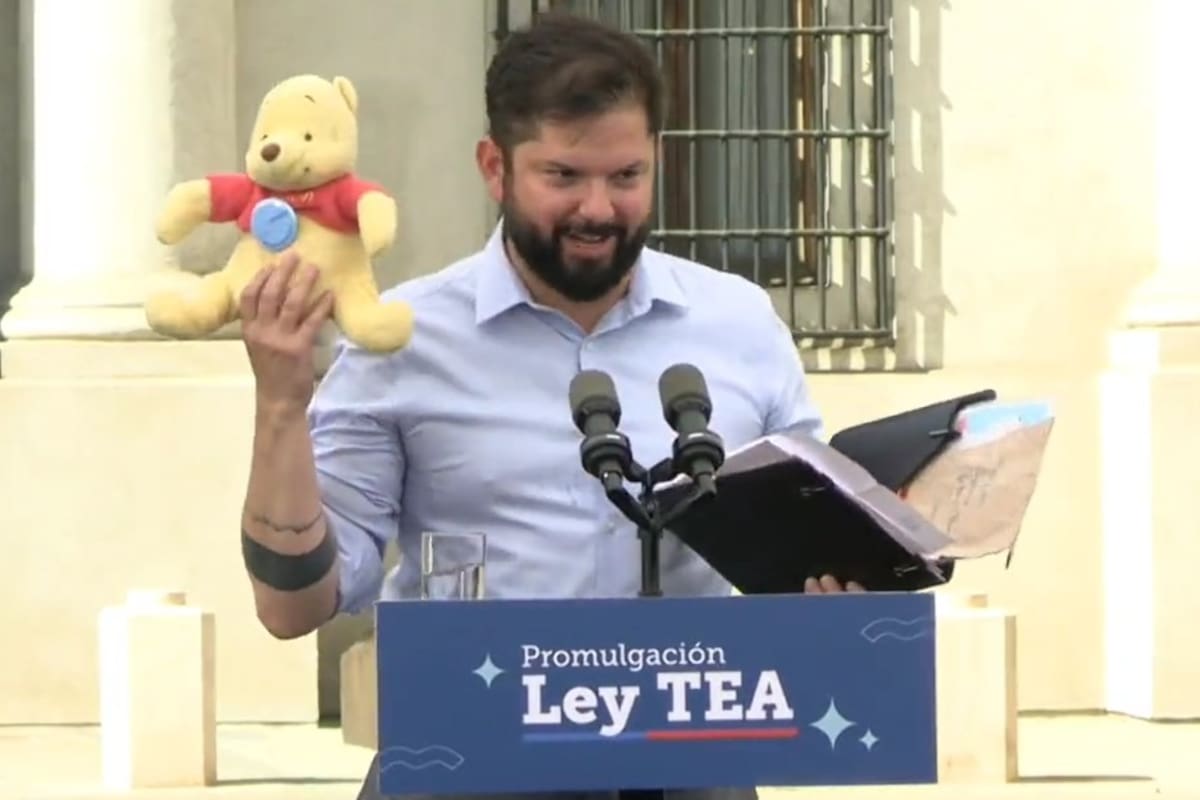 El presidente de Chile, Gabriel Boric, sostiene un peluche de Winnie de Pooh que le regaló un asistente