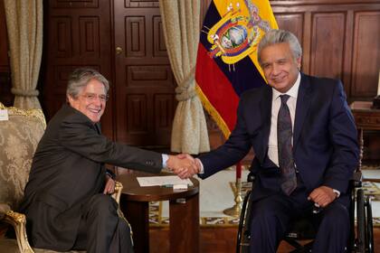 El presidente de Ecuador, Lenín Moreno, a la derecha, le da la mano al presidente electo Guillermo Lasso durante una reunión que forma parte del proceso de transición presidencial en Quito, Ecuador, el lunes 19 de abril de 2021. (Foto AP/Dolores Ochoa)