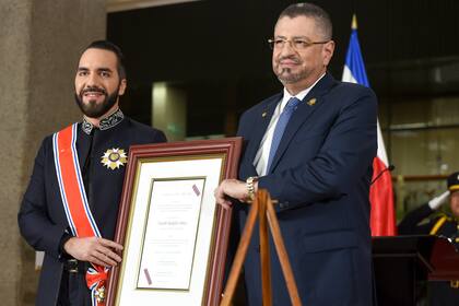 El presidente de El Salvador, Nayib Bukele, a la izquierda, recibe el más alto reconocimiento diplomático de Costa Rica de parte del presidente Rodrigo Chaves en el palacio presidencial en San José, Costa Rica, el lunes 11 de noviembre de 2024. (AP Foto/José Díaz)