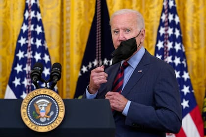 El presidente de Estados Unidos, Joe Biden, se quita la mascarilla a su llegada para hablar de la pandemia del coronavirus en la Sala Este de la Casa Blanca en Washington, el martes 3 de agosto de 2021. (AP Foto/Susan Walsh)