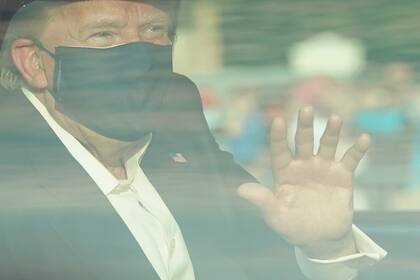 El presidente de Estados Unidos, Trump, saluda desde la parte trasera de un automóvil en una caravana fuera del Centro Médico Walter Reed en Bethesda, Maryland, el 4 de octubre de 2020