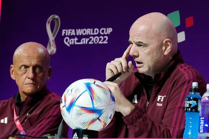 El presidente de la FIFA Gianni Infantino (derecha) charla con periodistas junto al director de la comisión de árbitros Pierluigi Collina (izquierda) en Doha, Qatar, el viernes 18 de noviembre de 2022. (AP Foto/Martin Meissner)