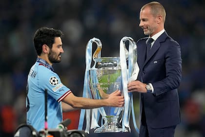 El presidente de la UEFA Aleksander Ceferin entrega el trofeo al capitán del Manchester City Ilkay Gundogan tras su victoria en la final de la Liga de Campeones ante el Inter de Milán, el sábado 10 de junio de 2013, en Estambul. (AP Foto/Francisco Seco)