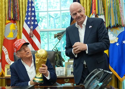 El presidente de los Estados Unidos Donald Trump sostiene el trofeo del campeón de la Copa Mundial de la FIFA en la Oficina Oval junto al presidente de la FIFA Gianni Infantino el viernes 22 de agosto del 2025. (AP Foto/Jacquelyn Martin)