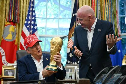 El presidente de los Estados Unidos, Donald Trump, acompañado por el presidente de la FIFA, Gianni Infantino, sostiene el trofeo de la Copa del Mundo
