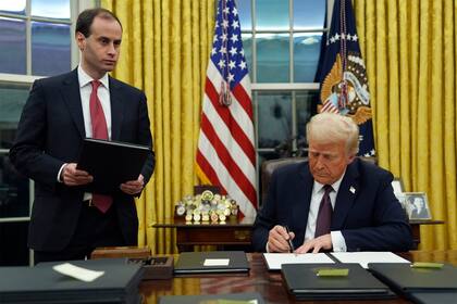 El presidente Donald Trump firma una orden ejecutiva para crear el Departamento de Eficiencia Gubernamental (DOGE) en el Despacho Oval de la Casa Blanca, el lunes 20 de enero de 2025, en Washington, mientras el secretario de despacho de la Casa Blanca, Will Scharf, observa. (AP foto/Evan Vucci)