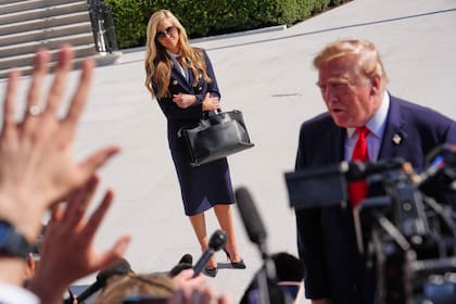 El presidente Donald Trump habla con los periodistas luego de la sesión informativa de la secretaria de Prensa, Katie Zacharia, en Washington, parada detrás de él.
