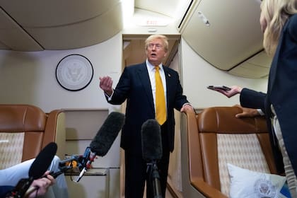 El presidente Donald Trump habla con reporteros a bordo del Air Force One.