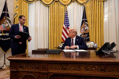 El presidente Donald Trump habla con Will Scharf, secretario de personal de la Casa Blanca, mientras firma órdenes ejecutivas en la Oficina Oval de la Casa Blanca, el jueves 23 de enero de 2025, en Washington. (AP Foto/Ben Curtis)