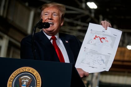 El presidente Donald Trump sostiene un gráfico que documenta la pérdida de tierras de ISIS en Irak y Siria en un discurso pronunciado en la planta de tanques.