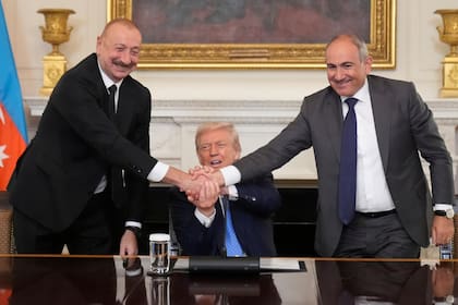 El presidente estadounidense, Donald Trump, centro, une sus manos con la del primer ministro armenio Nikol Pashinyan, derecha, y la del presidente de Azerbaiyán Ilham Aliyev en la ceremonia de firma de un acuerdo trilateral en el Comedor de Estado de la Casa Blanca, el viernes 8 de agosto de 2025, en Washington. (AP Foto/Mark Schiefelbein)