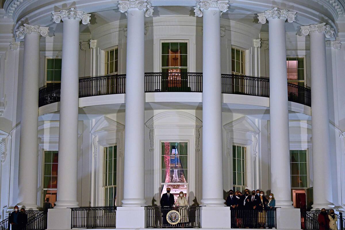El presidente estadounidense Joe Biden (CL) y la primera dama Jill Biden (CR) aparecen en el balcón de la habitación azul mientras ellos y sus familiares (derecha) ven los fuegos artificiales desde la Casa Blanca en Washington
