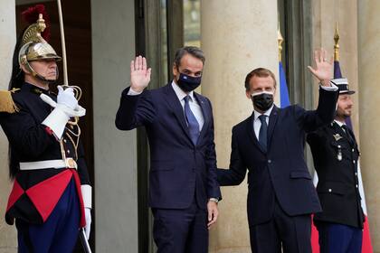 El presidente francés, Emmanuel Macron (izquierda), y el primer ministro griego, Kyriakos Mitsotakis (centro), saludan el martes 28 de septiembre de 2021 en el Palacio del Elíseo en París. (AP Foto/Francois Mori)