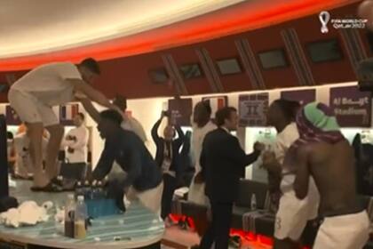 El presidente francés Emmanuel Macron saluda a los jugadores del seleccionado de su país en medio de la celebración en los vestuarios, con Giroud subido a una mesa.