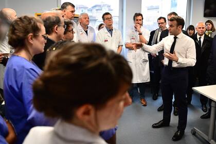 El presidente francés, Emmanuel Macron, se reúne con el personal médico mientras visita el hospital Pitie-Salpetriere en París el 27 de febrero de 2020, donde la primera víctima francesa de COVID-19 falleció el día anterior.