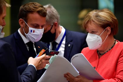El presidente francés, Emmanuel Macron, toma una foto de un documento mientras la canciller alemana Angela Merkel lo sostiene durante una cumbre de la UE en Bruselas el 20 de julio de 2020