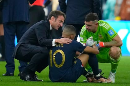El presidente francés, Emmanuel Macron y el Dibu Martínez, arquero argentino, consuelan a Mbappé