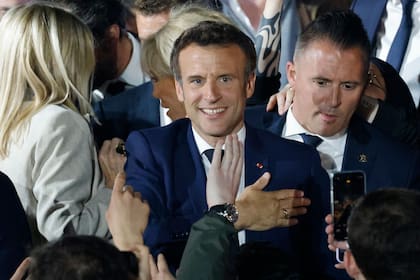 El presidente francés y candidato del partido La Republique en Marche (LREM) a la reelección, Emmanuel Macron, se pone la mano sobre el corazón mientras saluda a sus seguidores tras su victoria en las elecciones presidenciales de Francia, en el Campo de Marte de París, el 24 de abril de 2022.