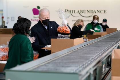 El presidente Joe Biden y la primera dama Jill Biden empacan zanahorias y manzanas el domingo en el banco de alimentos Philabundance, el 16 de enero de 2022, en Filadelfia. (AP Foto/Patrick Semansky)