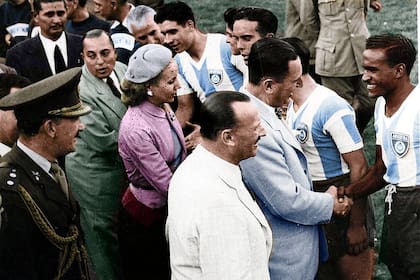 El presidente Juan Domingo Perón y su esposa, Eva Duarte, saludan al plantel argentino que ganó la medalla de oro en los Juegos Panamericanos realizados en Buenos Aires, en 1951. En primer plano, de saco blanco, aparece Carlos Paillot, presidente de Racing. De verde, detrás de la primera dama, está el ministro de Hacienda, Luis Cereijo.