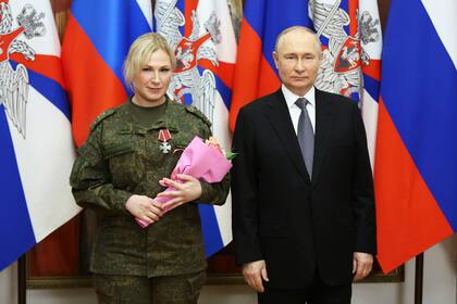 El presidente ruso, Vladimir Putin, a la derecha, posa para una foto con una militar (no se proporciona el nombre) en una ceremonia de premiación durante su visita a la sede del Distrito Militar del Sur