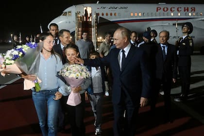 El presidente ruso Vladímir Putin, derecha, recibe a los presos rusos liberados en un canje con Estados Unidos y a sus familiares, en el aeropuerto gubernamental Vnukovo en las afueras de Moscú, Rusia, el jueves 1 de agosto de 2024. (Mikhail Voskresensky, Sputnik, Kremlin Pool Photo via AP)