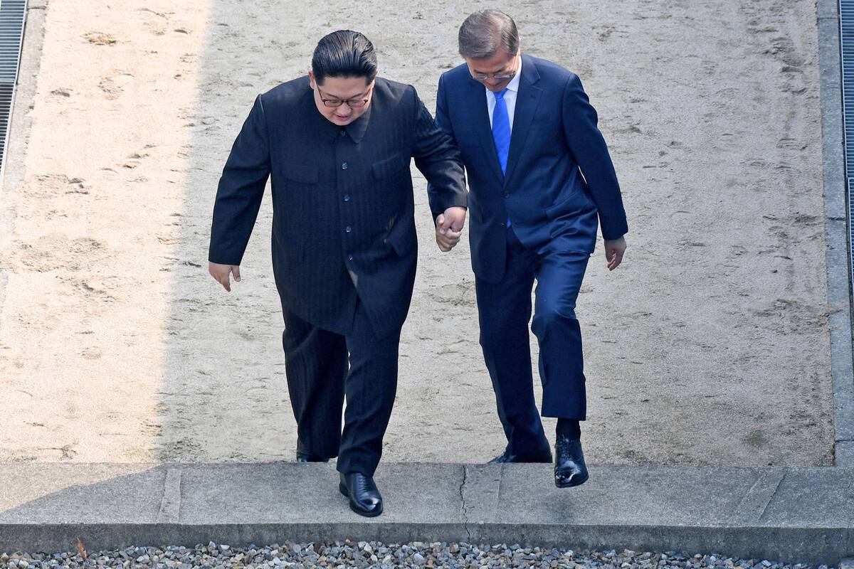 El presidente surcoreano Moon Jae-in y el líder norcoreano Kim Jong Un al cruzar la frontera